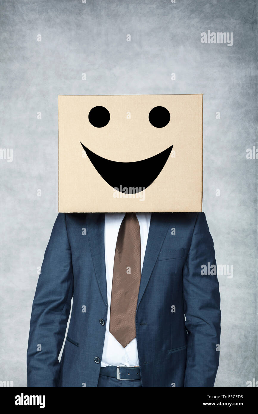 Business man is a happy, fake smile of businessman hiding head inside the box Stock Photo