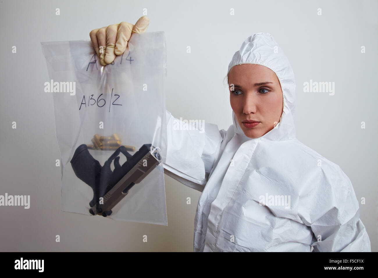 Female forensic scientist holding weapon and ammunition Stock Photo