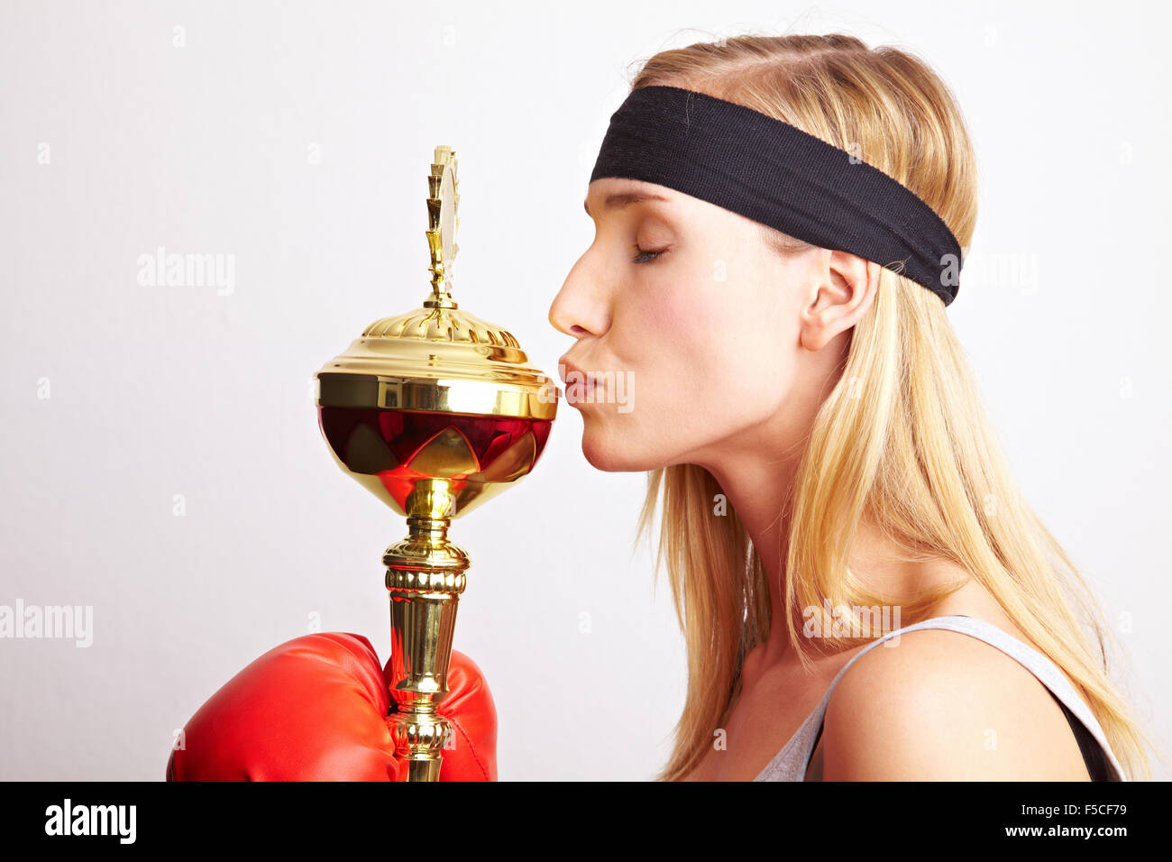 Young female boxer with red boxing gloves kissing a trophy Stock Photo