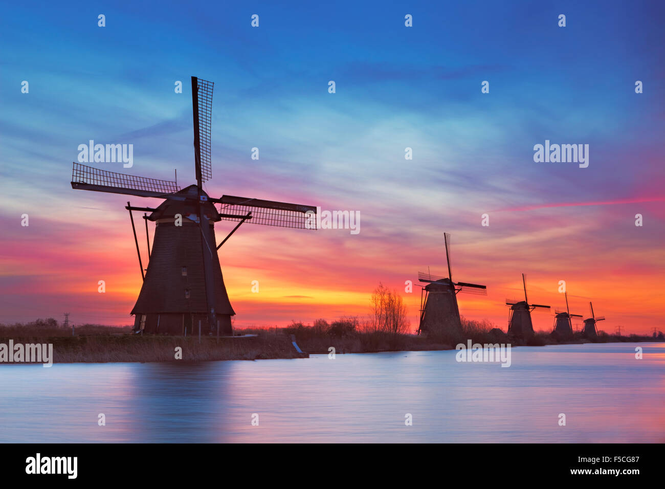 Traditional Dutch windmills with a colourful sky just before sunrise. Photographed at the famous Kinderdijk. Stock Photo