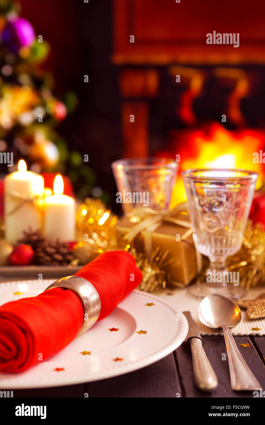 A romantic Christmas dinner table setting with candles and Christmas decorations. A fire is burning in the fireplace and Christm Stock Photo