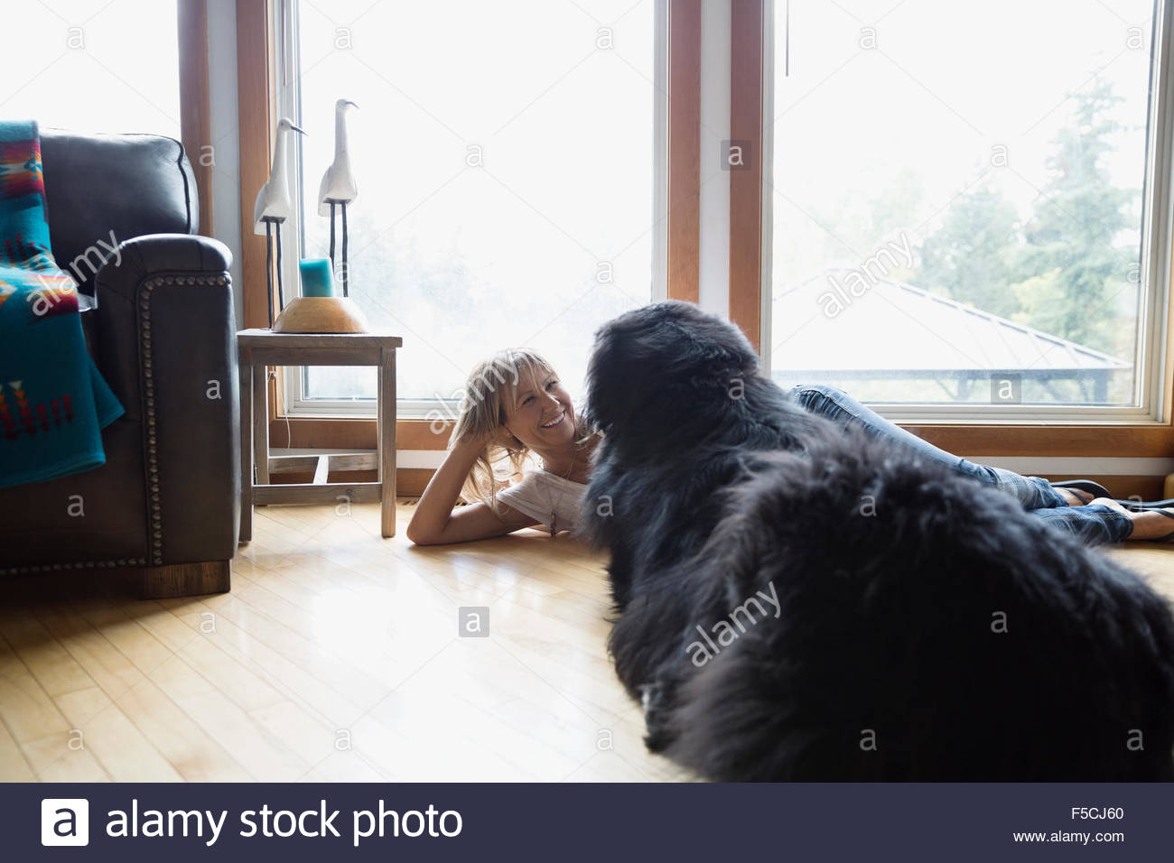 Woman and dog laying face to face floor Stock Photo