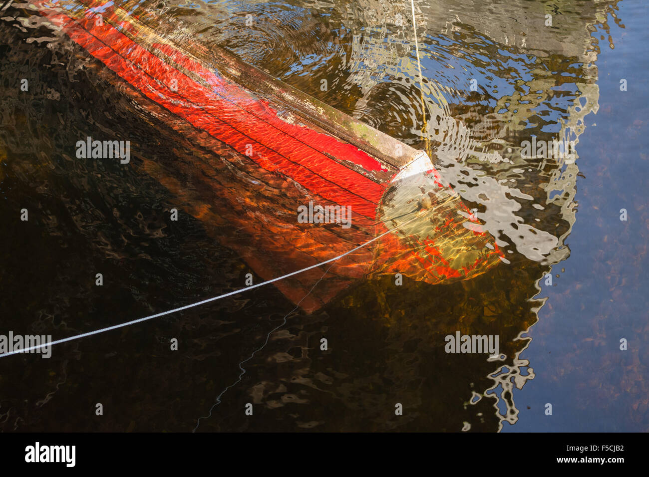 sinking boat - old red wooden rowing boat submerged under water Stock Photo