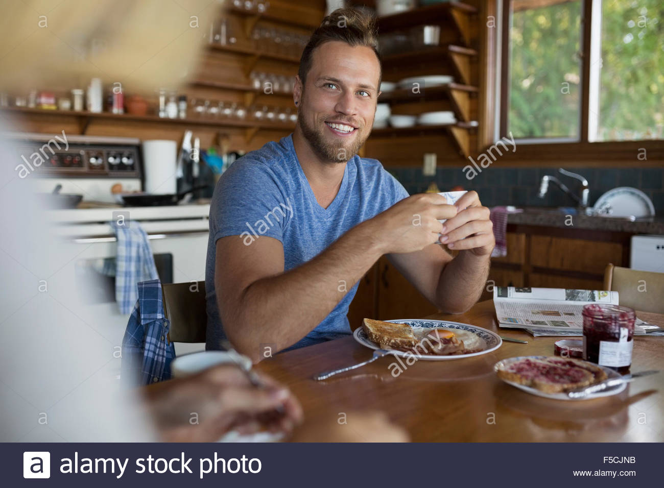 Smiling young couple enjoying breakfast at kitchen table Stock Photo