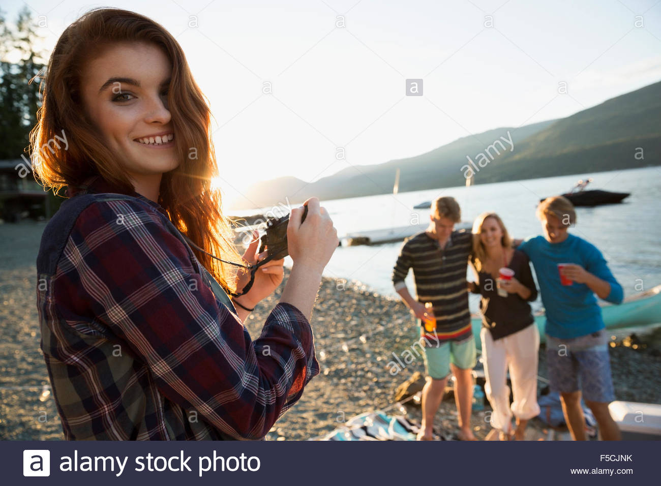 Portrait smiling young woman with friends at lakeside Stock Photo