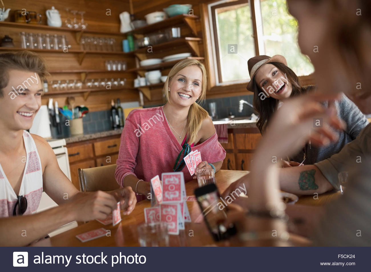 Young friends playing cards at cabin kitchen table Stock Photo