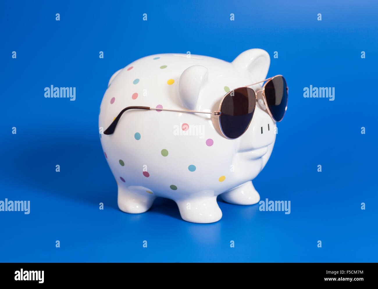 Piggy bank with sunglasses on blue background Stock Photo - Alamy