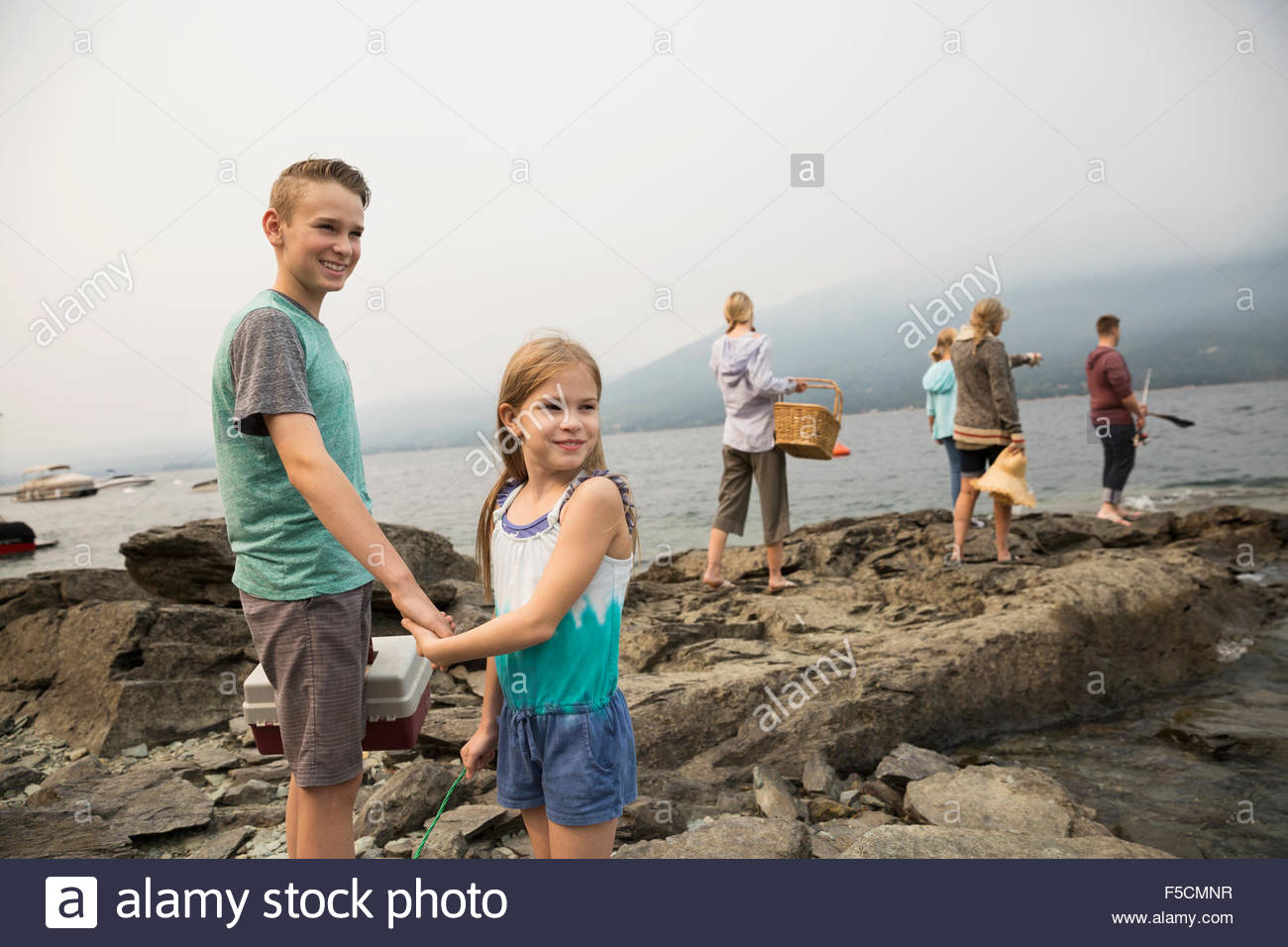 Brother sister tackle box holding hands rocks lakeside Stock Photo