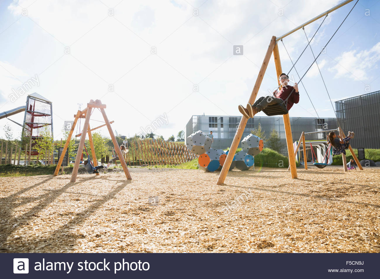 Boy swinging at sunny playground Stock Photo