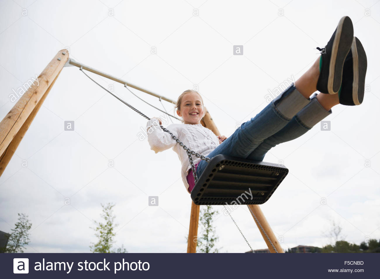 Portrait smiling girl swinging at playground Stock Photo