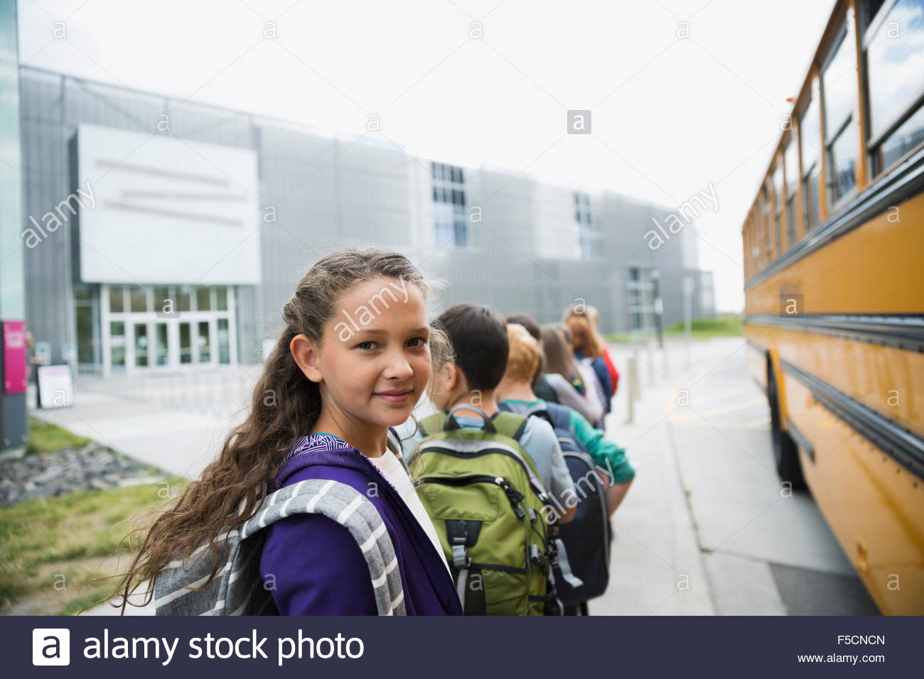 Portrait smiling schoolgirl arriving science center with classmates Stock Photo
