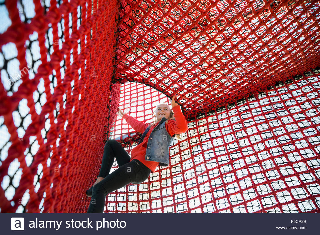 Girl climbing rope net at playground Stock Photo