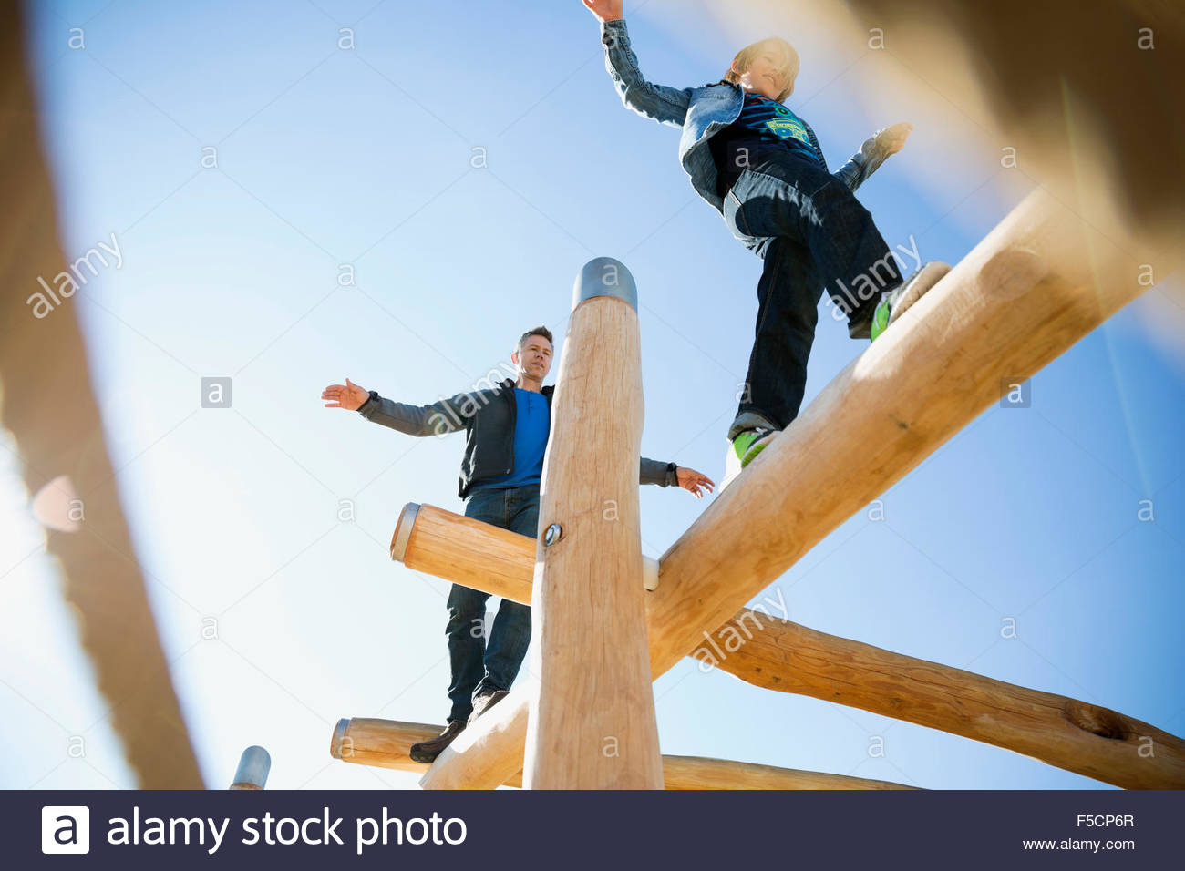 Father and son balancing logs sunny playground Stock Photo
