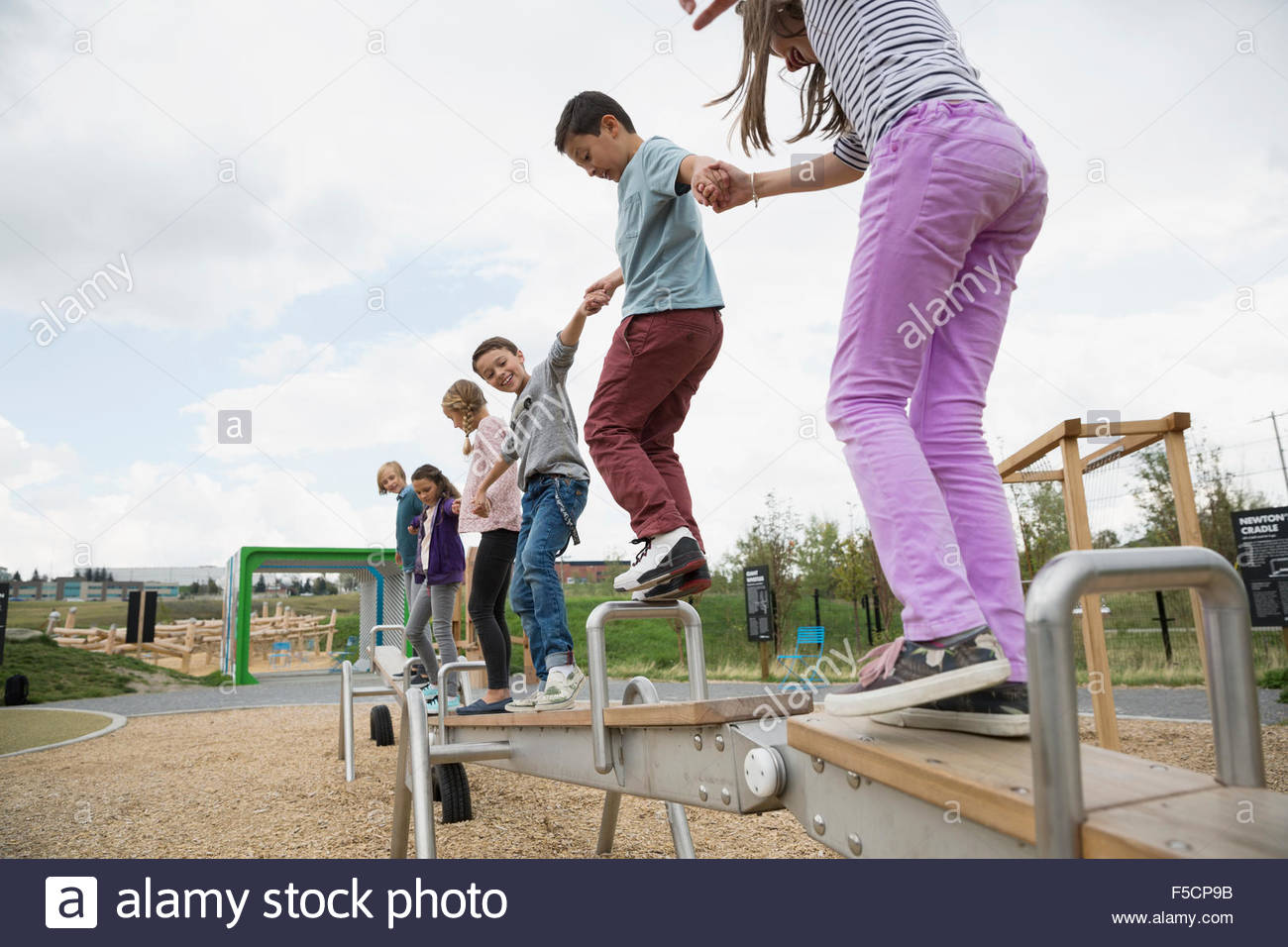 Kids balancing on long seesaw at playground Stock Photo