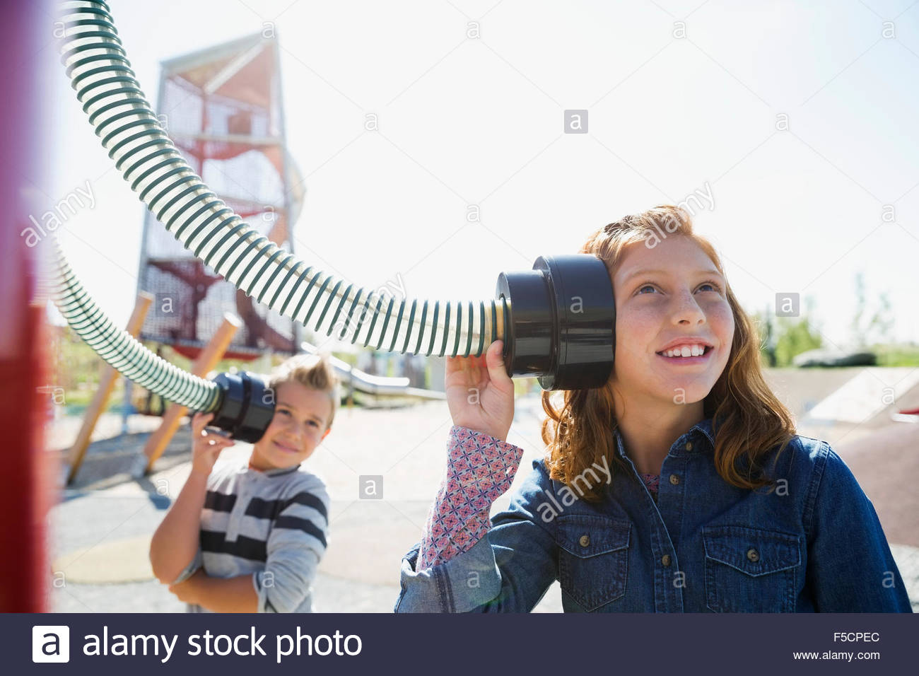Boy and girl listening to tubes sunny playground Stock Photo