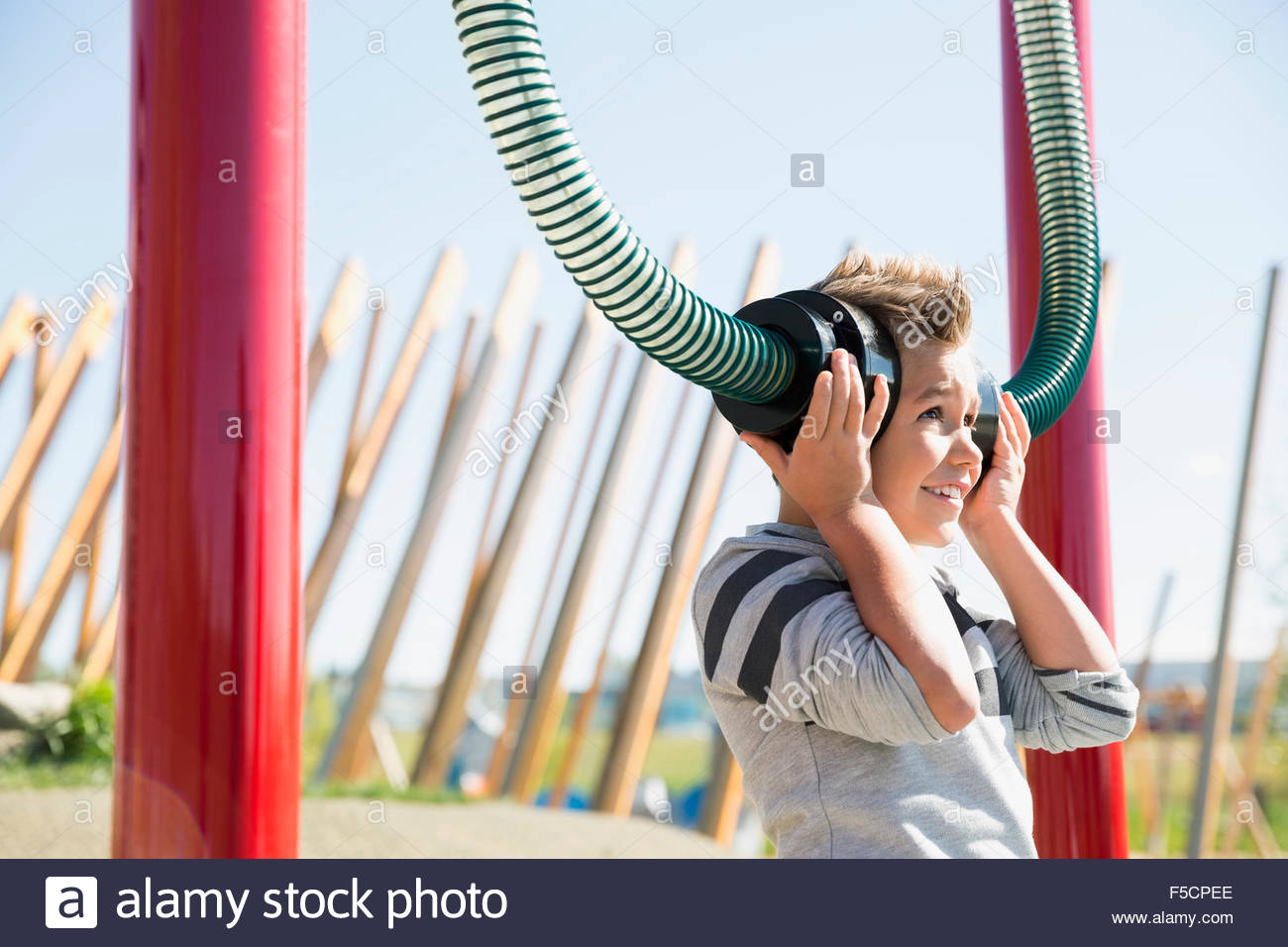 Boy playing listening to tubes in sunny playground Stock Photo