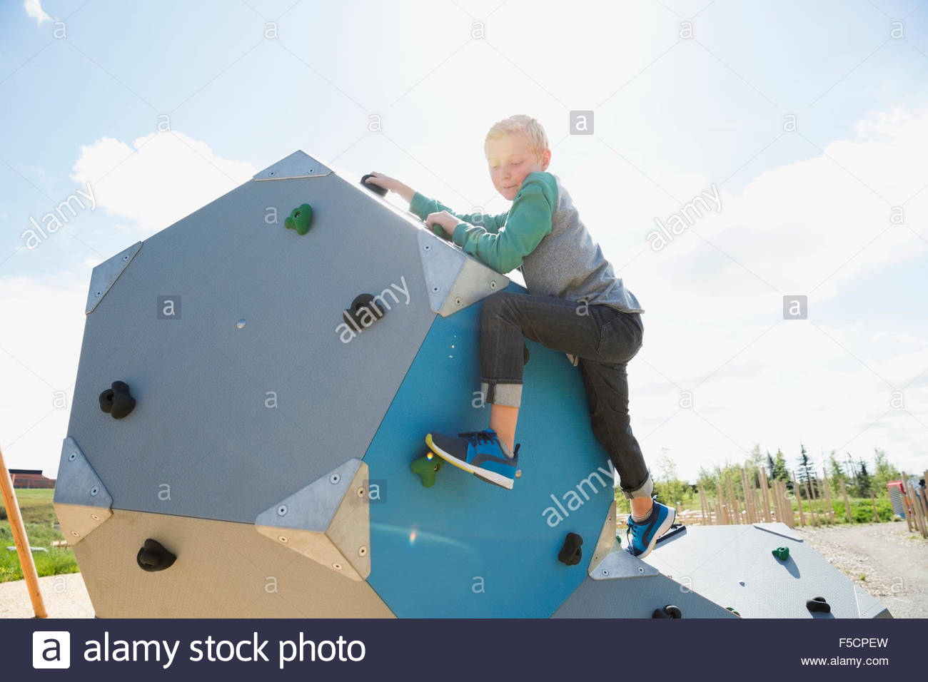 Boy climbing geometric shapes at sunny playground Stock Photo