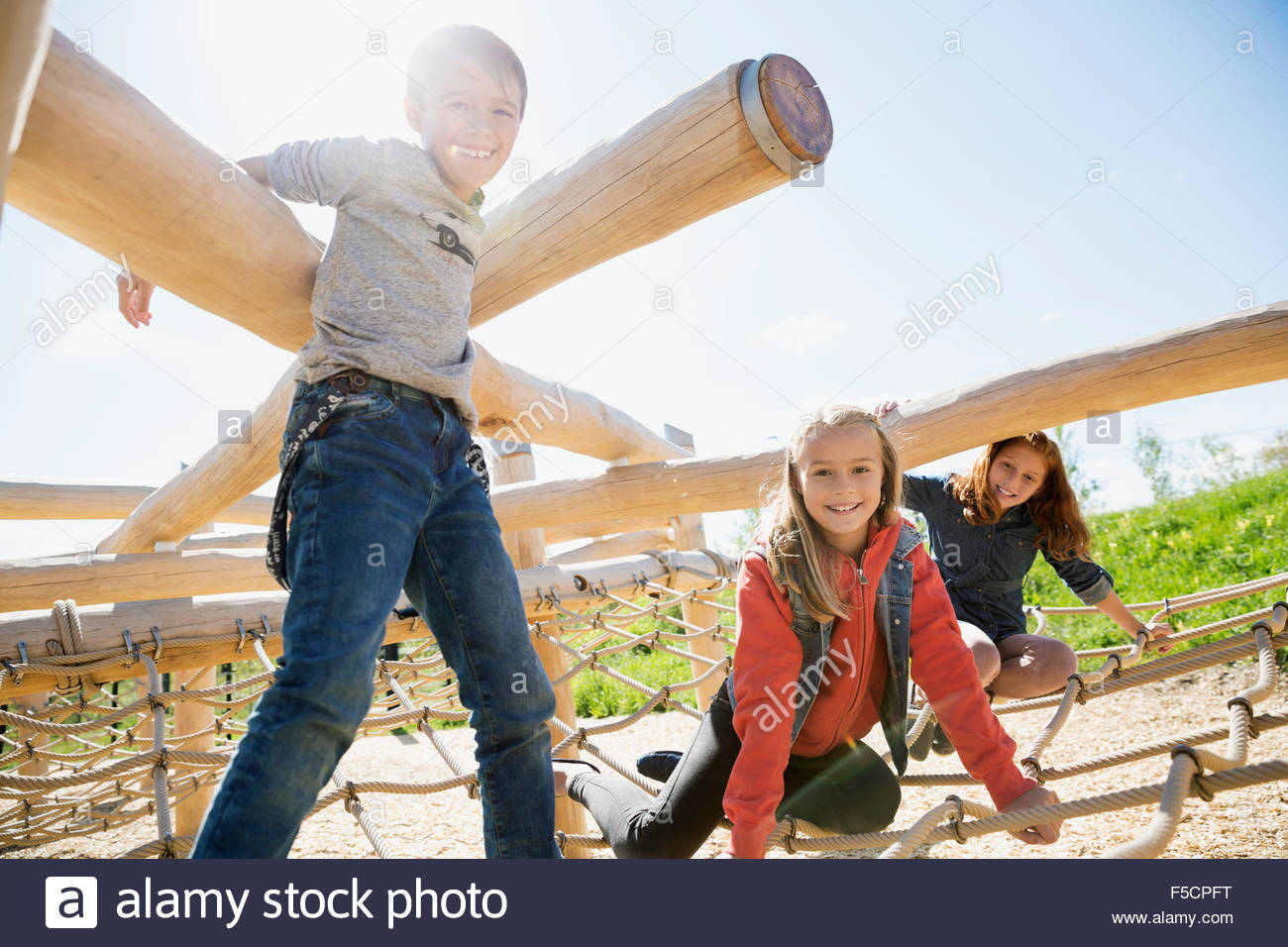 Portrait kids playing logs and net sunny playground Stock Photo