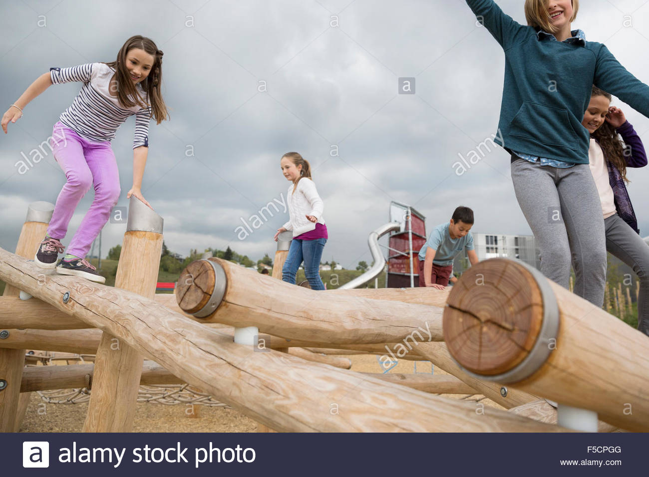 Kids playing on logs at playground Stock Photo