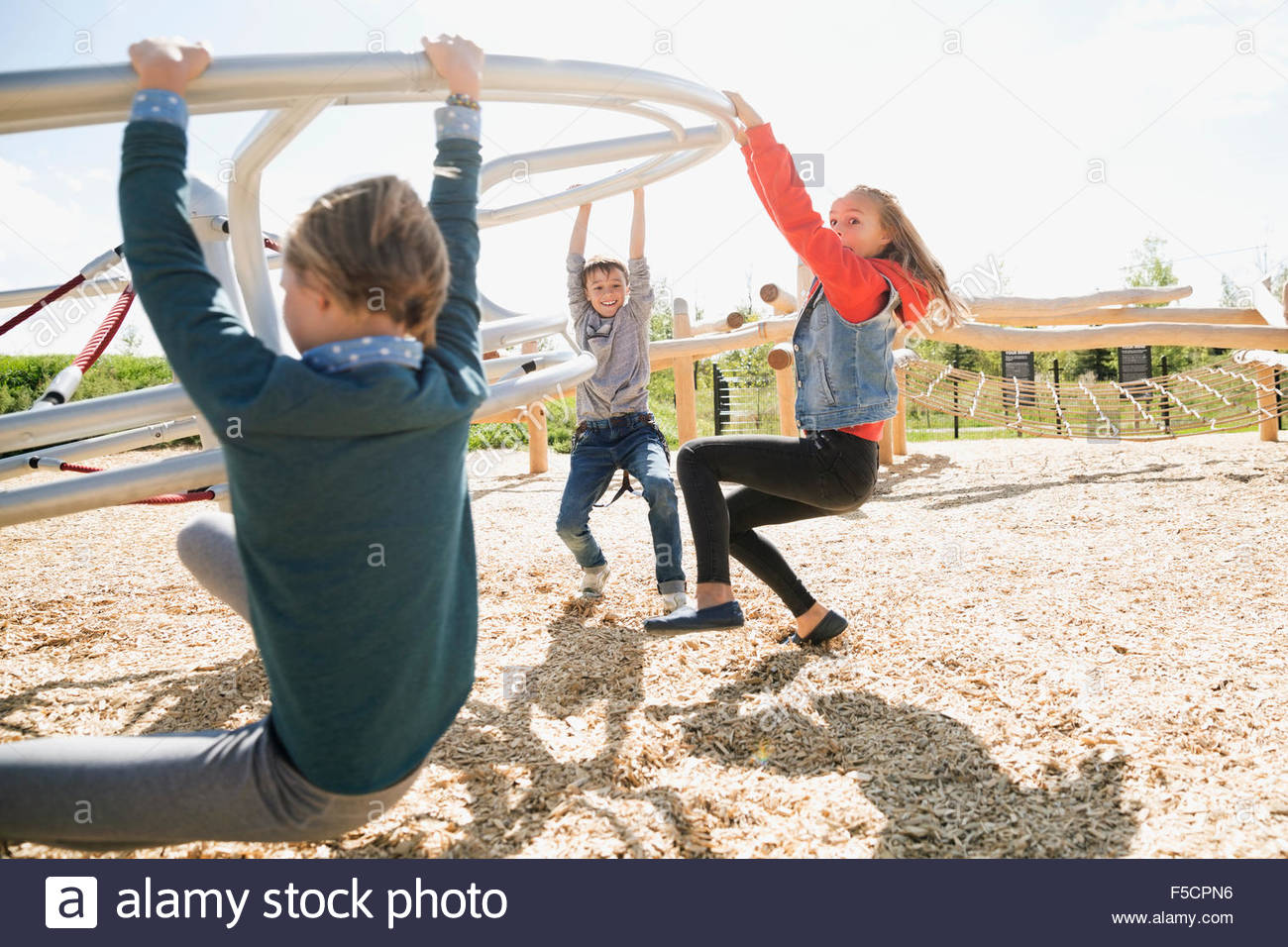 Kids hanging from spinning bar at sunny playground Stock Photo