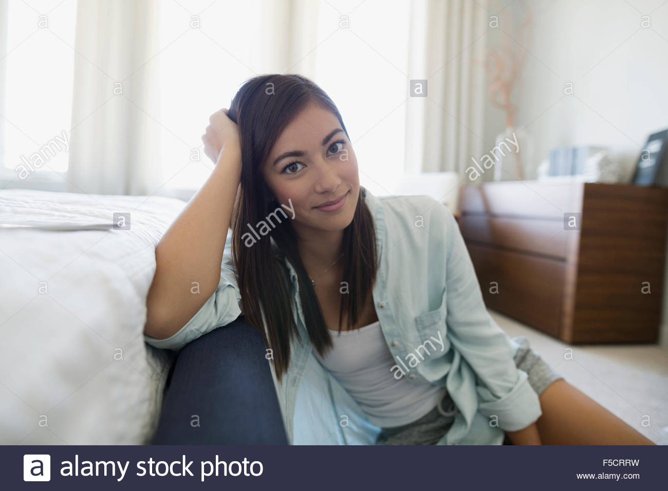Portrait smiling young woman leaning on bed Stock Photo Alamy