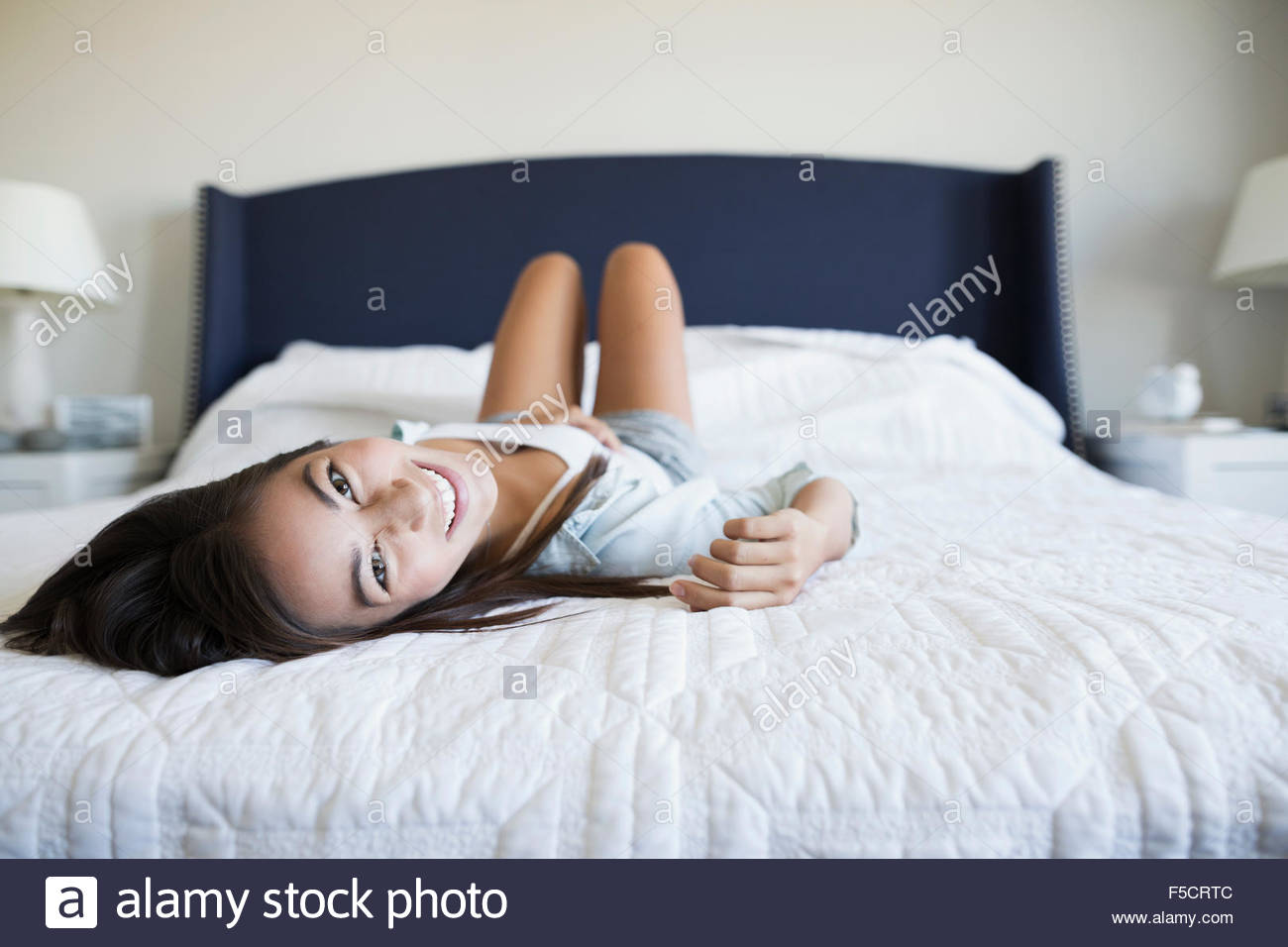 Portrait smiling young woman laying on bed Stock Photo