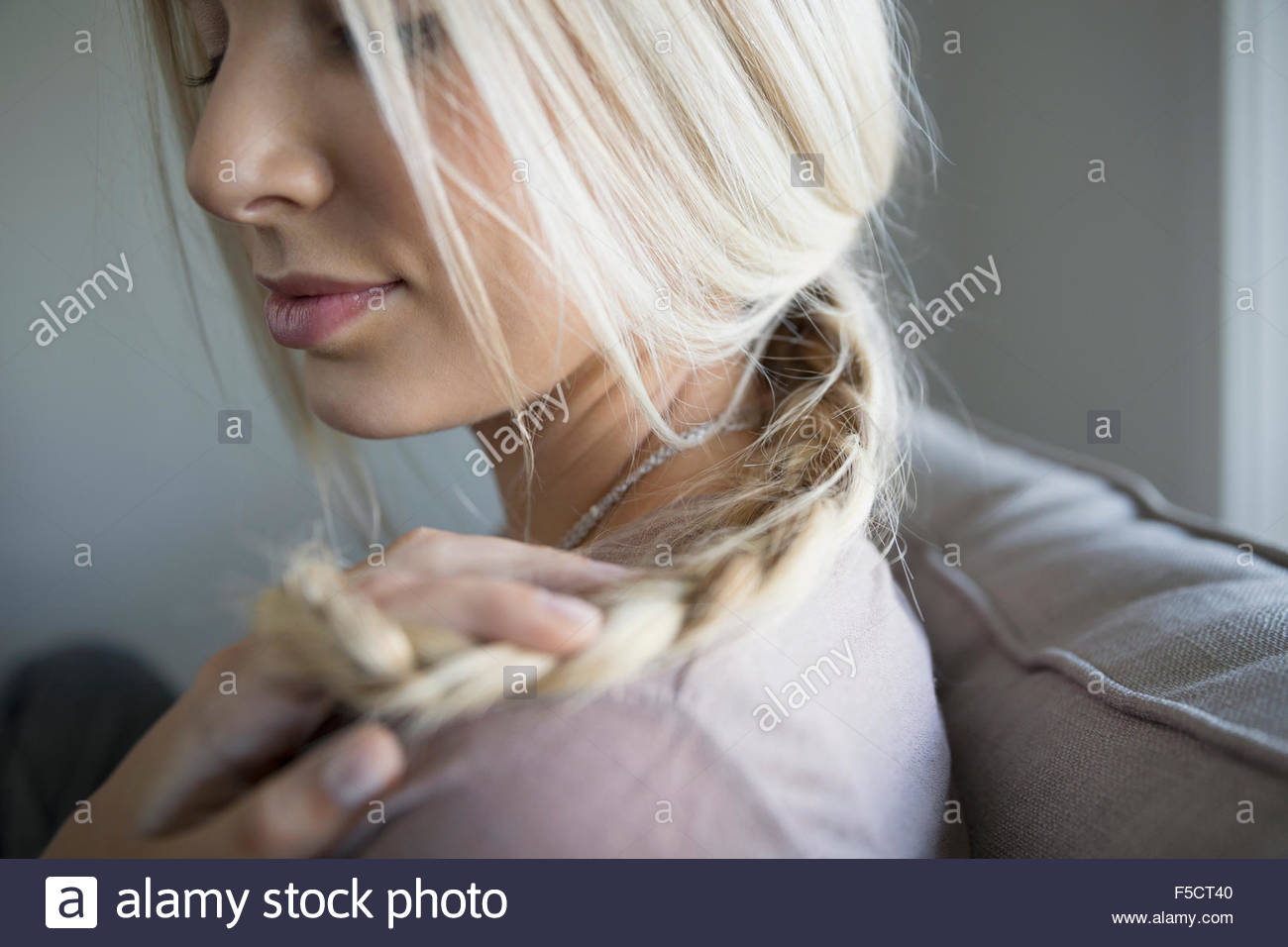Close up blonde young woman holding braid Stock Photo