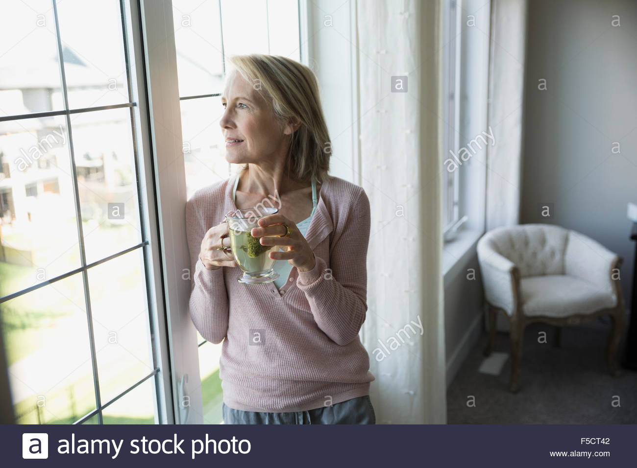 Senior woman drinking tea at living room window Stock Photo - Alamy