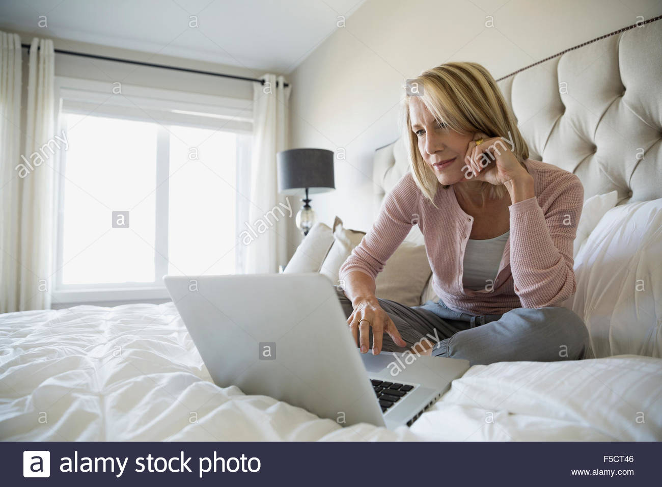 Woman using laptop in bed Stock Photo