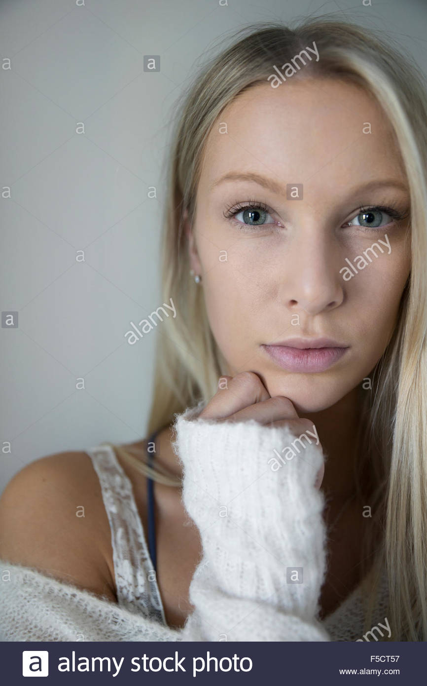 Portrait serious blonde woman with hand on chin Stock Photo