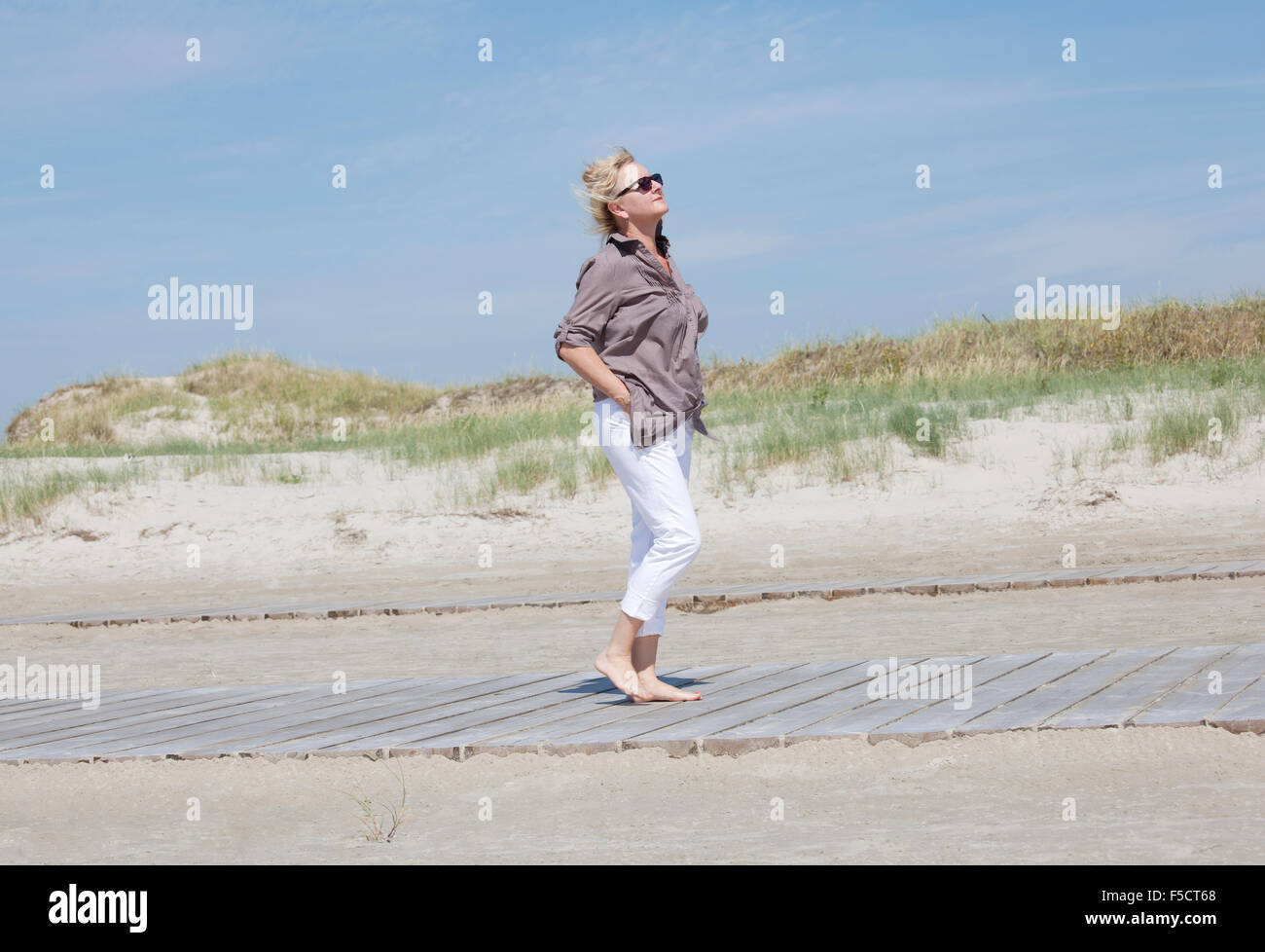 One Senior walks in the dunes on a beach and enjoying the peace and quiet Stock Photo