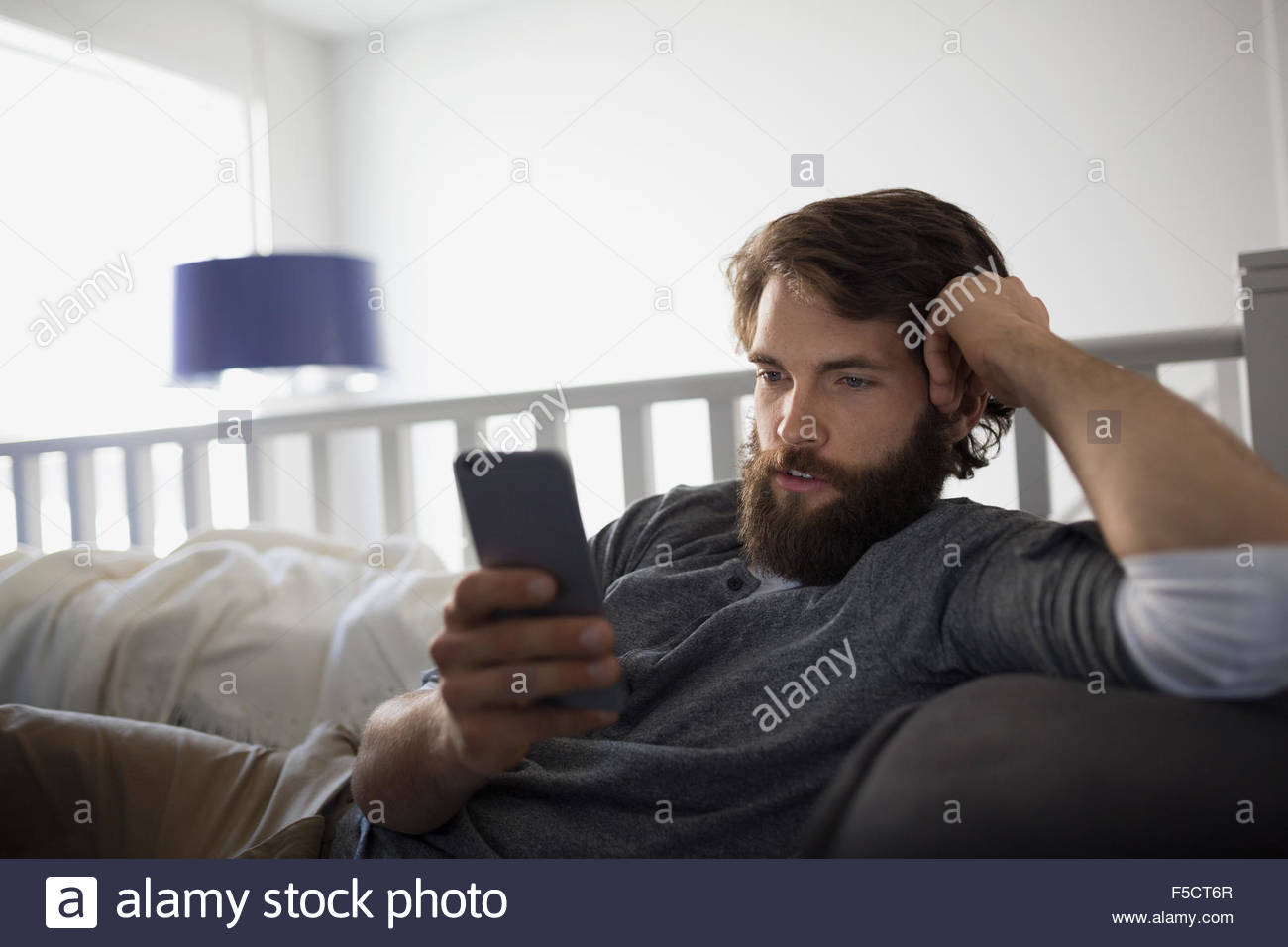 Man texting with cell phone on sofa Stock Photo
