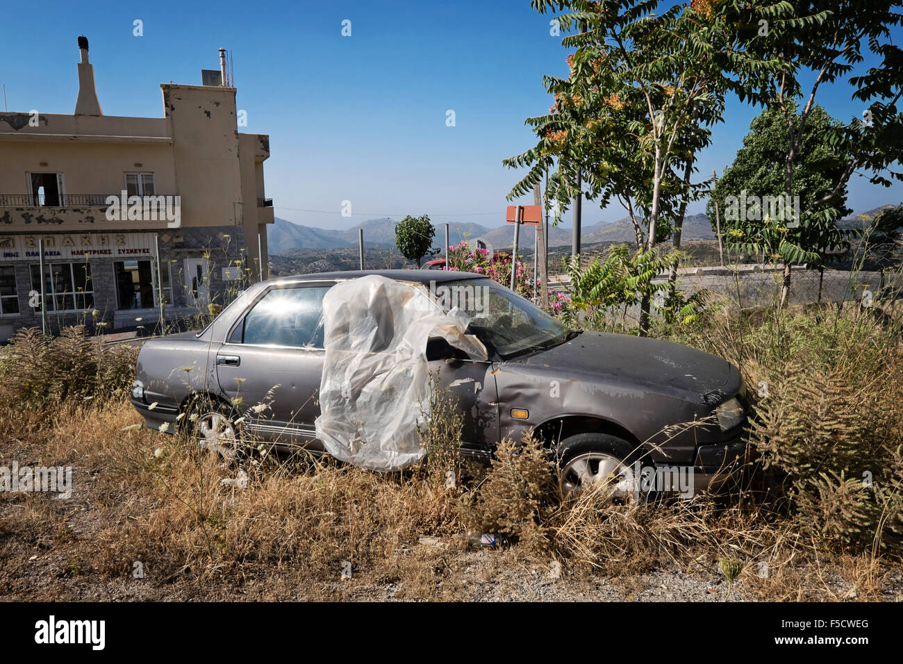 An abandoned car on a vacant lot in the village of Anogia on the island of Crete in Greece Stock Photo