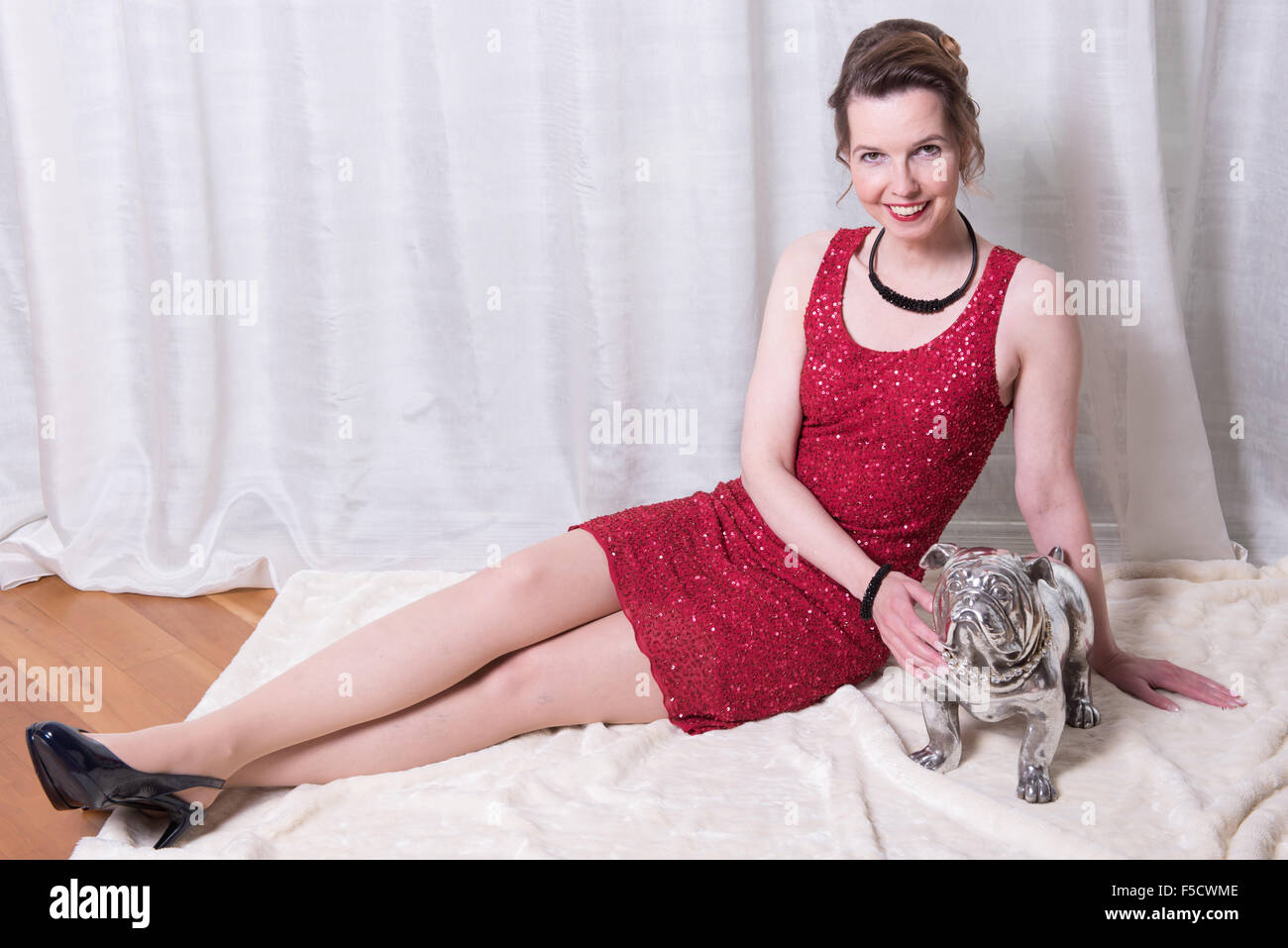 woman in red dress with dog on blanket Stock Photo