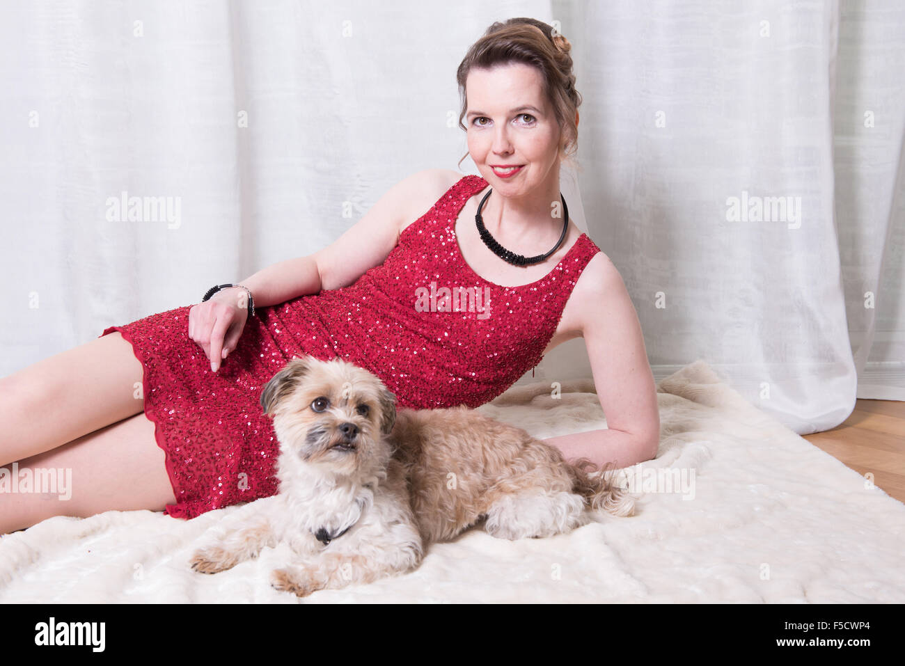 woman in red dress with dog on blanket Stock Photo