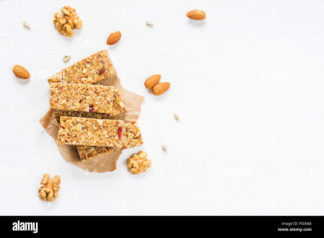 Granola bar or energy bar with oats, dates and nuts on white wooden