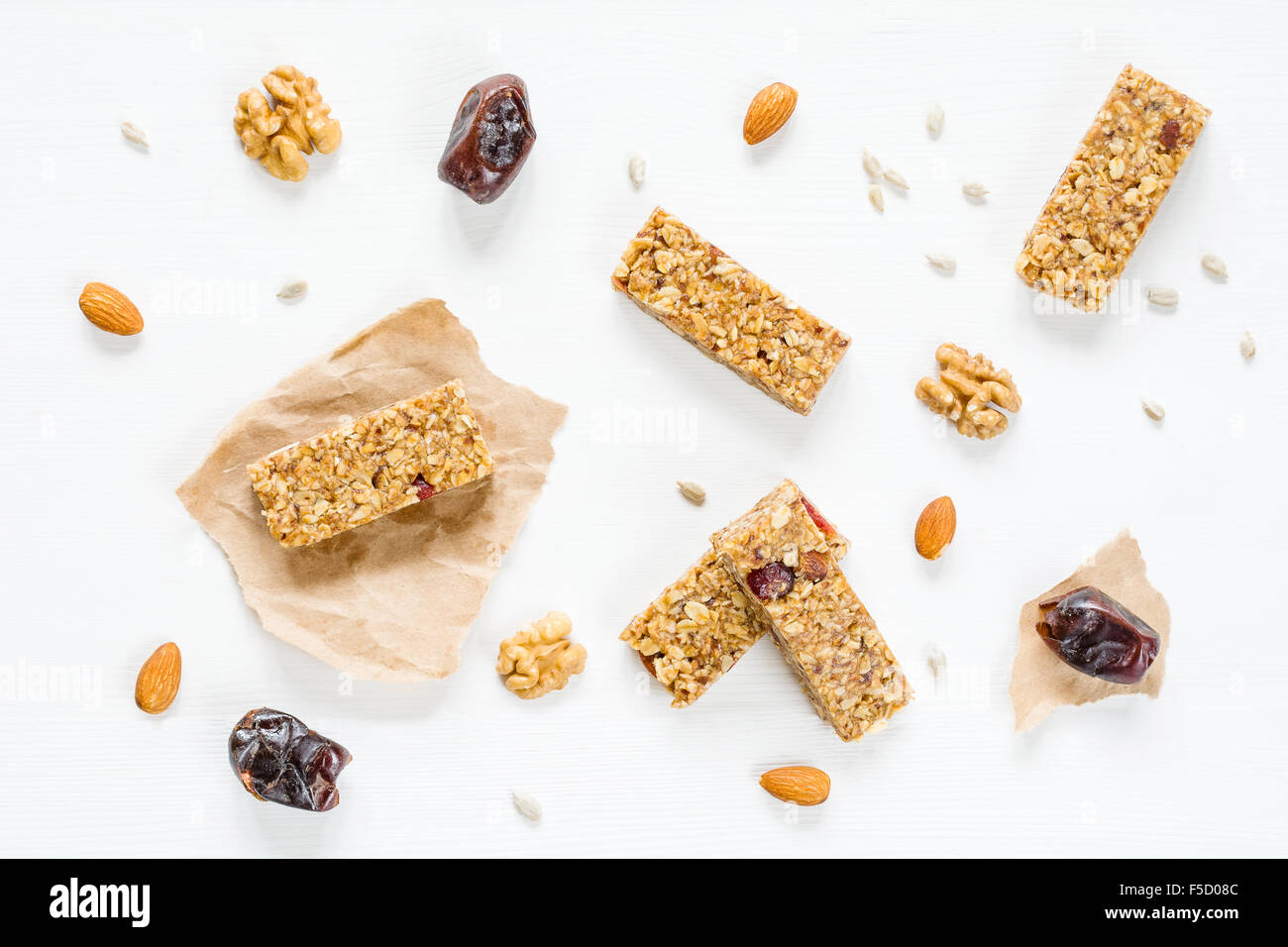 Granola bar or energy bar with oats, dates and nuts on white wooden background, top view. Snack