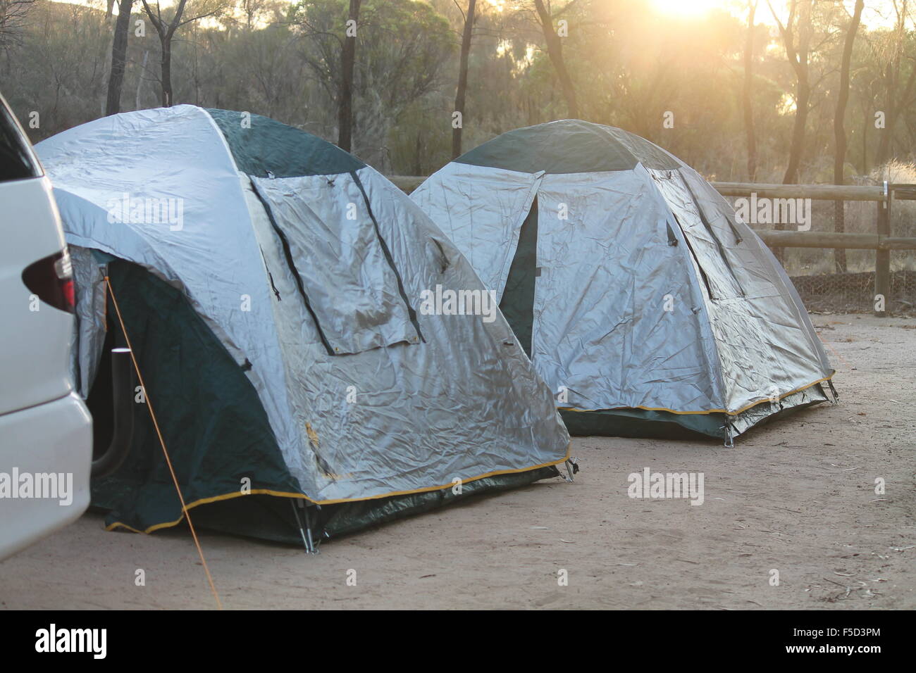 Two three man tents pitched at Wave Rock Camp Ground in Hyden, Western Australia while the sun is setting in the background. Stock Photo