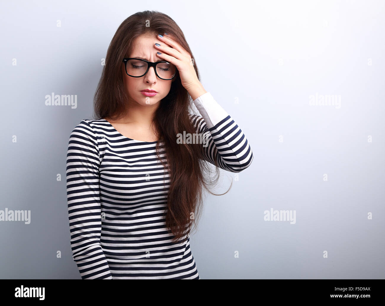 Beautiful business woman with headache holding head the hand with unhappy emotion on blue background Stock Photo