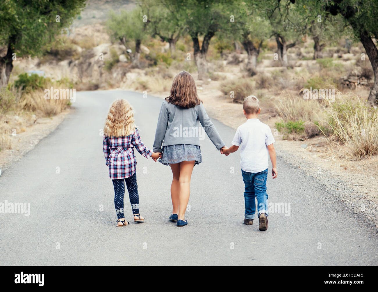 Three young children are on the road Stock Photo