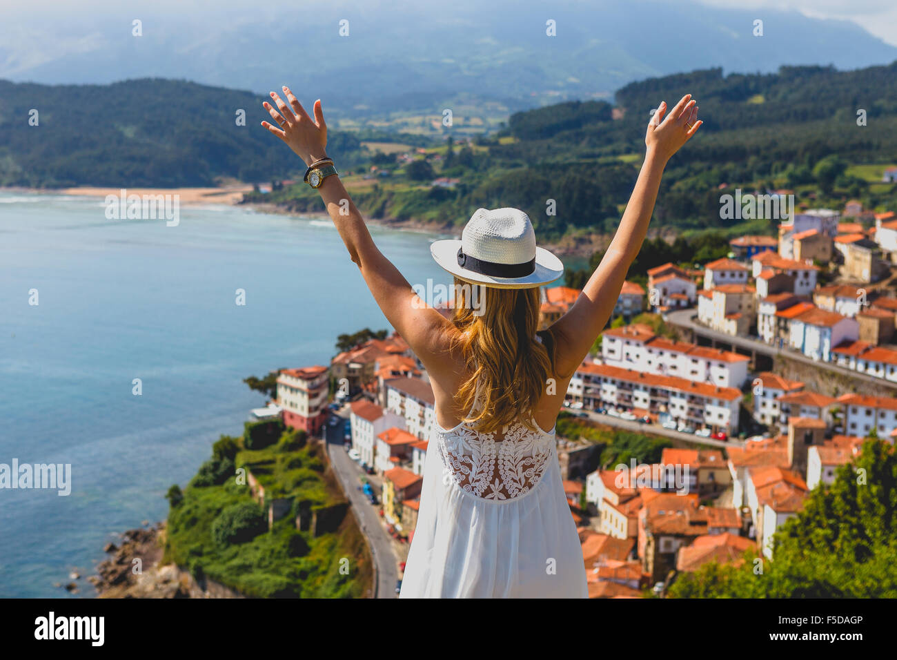 A beautiful young woman admiring the Lastres view from San Roque Viewpoint, Concejo de Colunga, Asturias, Spain. Stock Photo