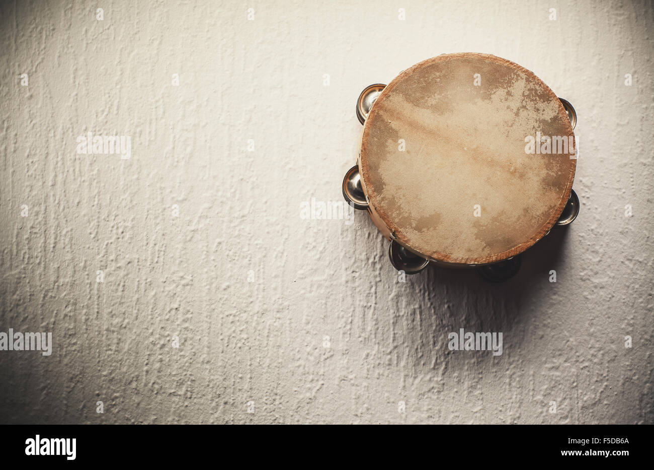Old wooden tambourine hanged on the white wall. Stock Photo