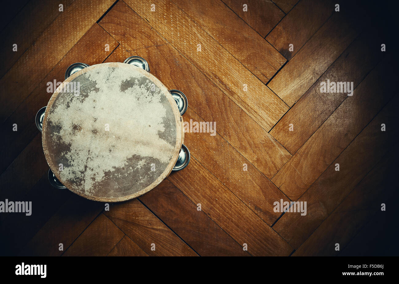 Old wooden tambourine on brown parquet. Stock Photo