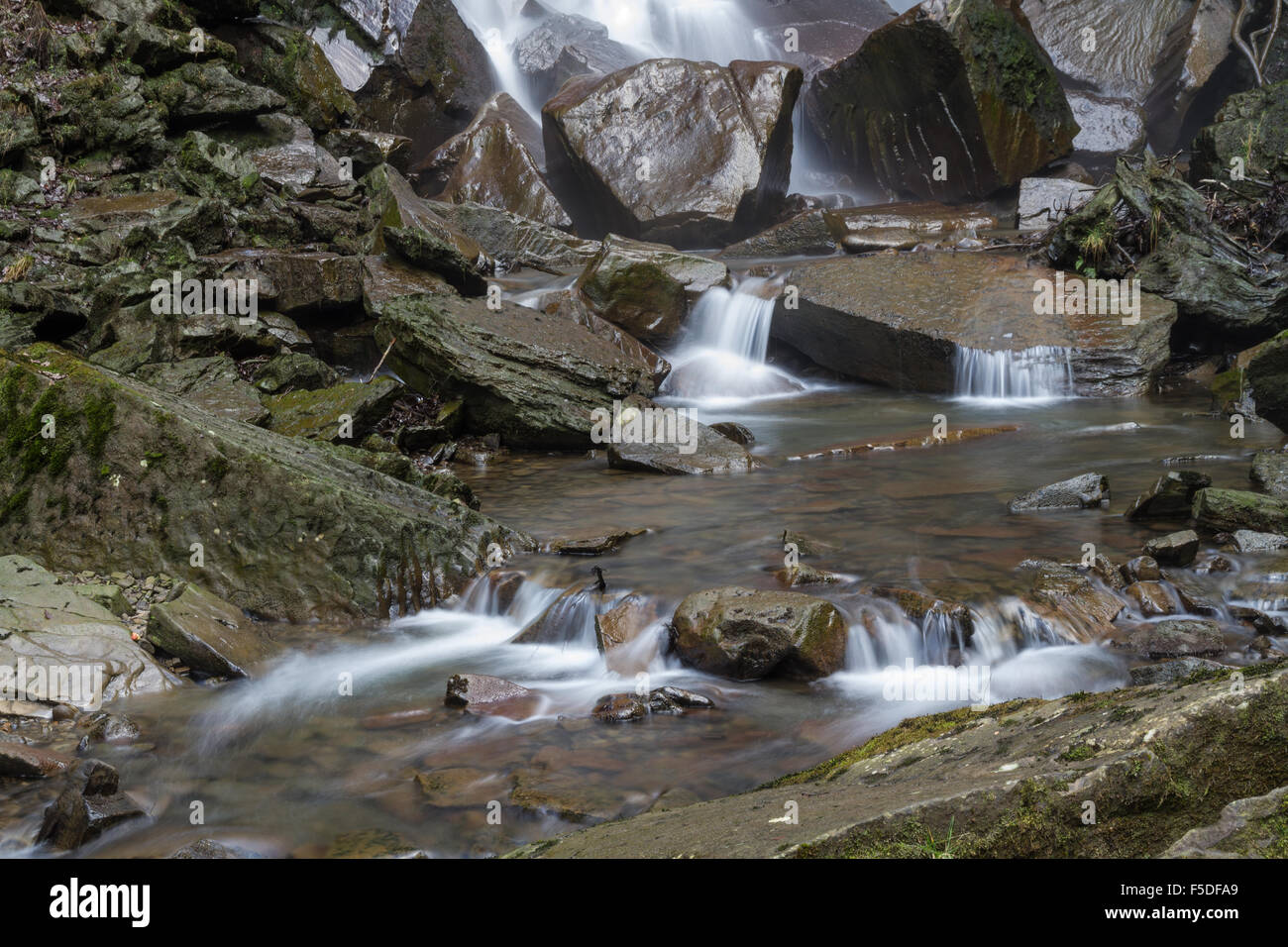 Detail of water cascading onto rocks at the bottom of a waterfall Stock