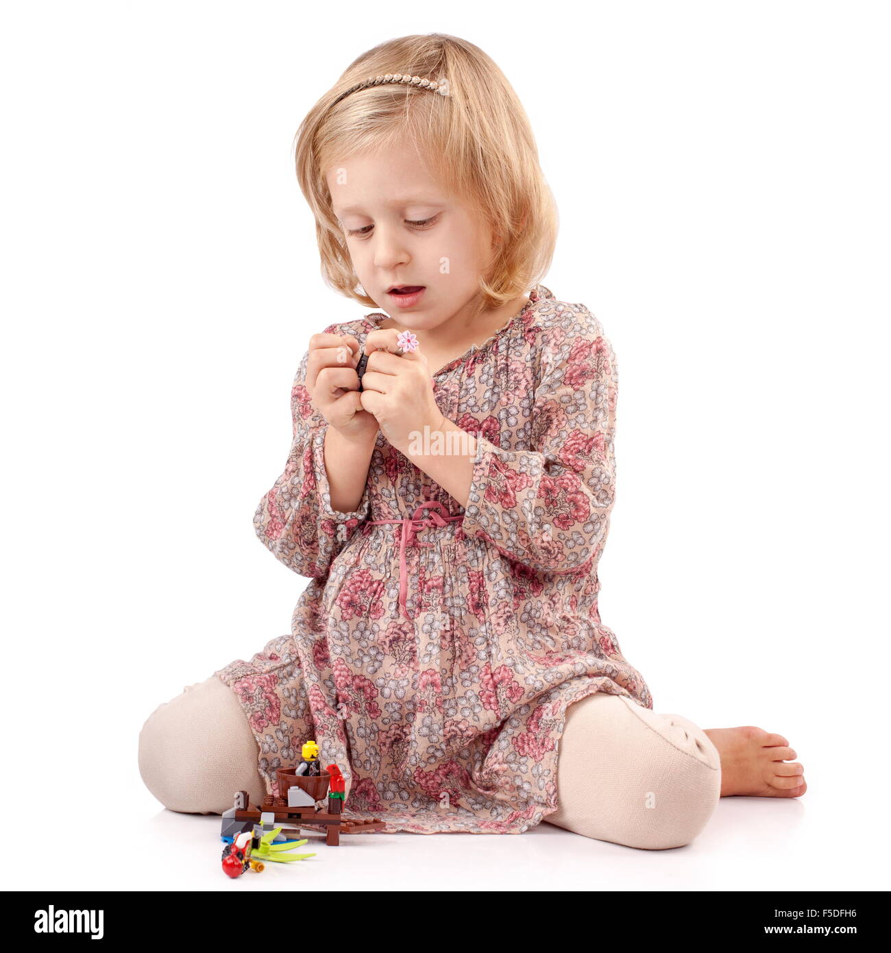 Very thoughtful girl playing with small toys Stock Photo