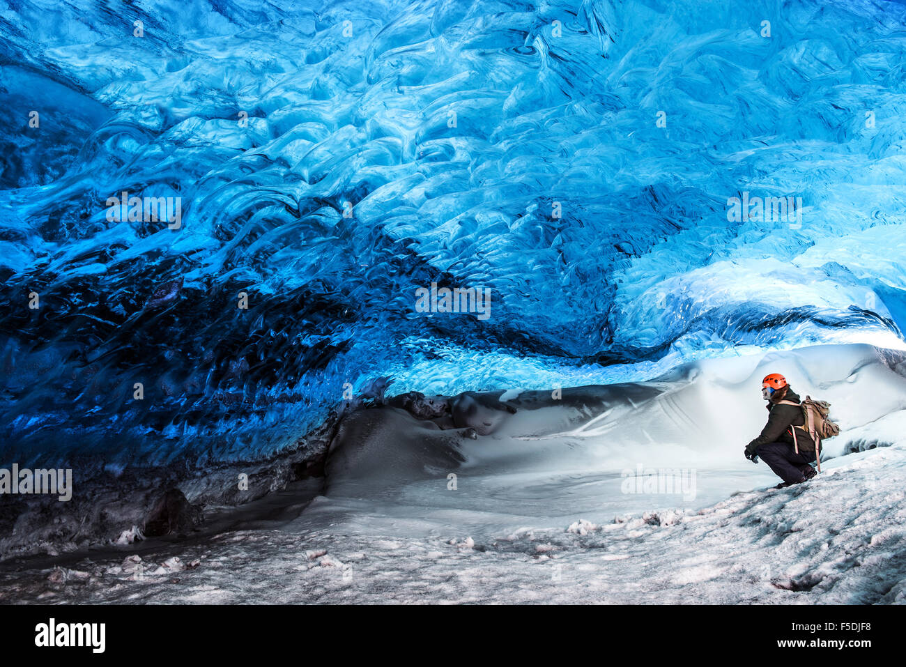 Man traveler enjoying exotic landmark, sitting in the ice cave, Skaftafell glacier, Vatnajokull National park, amazing nature Stock Photo