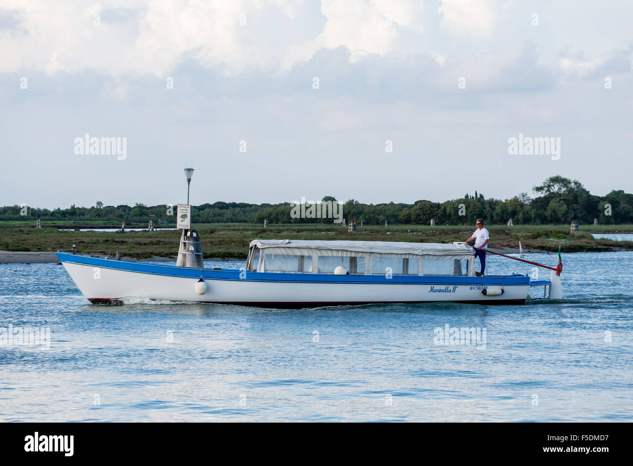 A man steering a boat through a Venice canal with an old fashioned