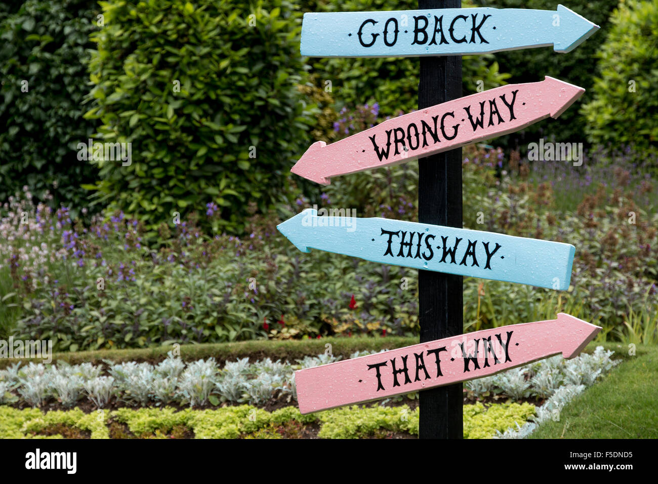 Confusing directions sign from the Alice Garden at Guildford Castle. Stock Photo