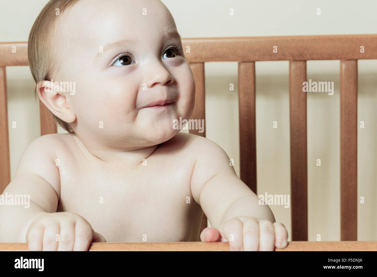 Funny Little Baby With Beautiful Standing In A Round White Crib