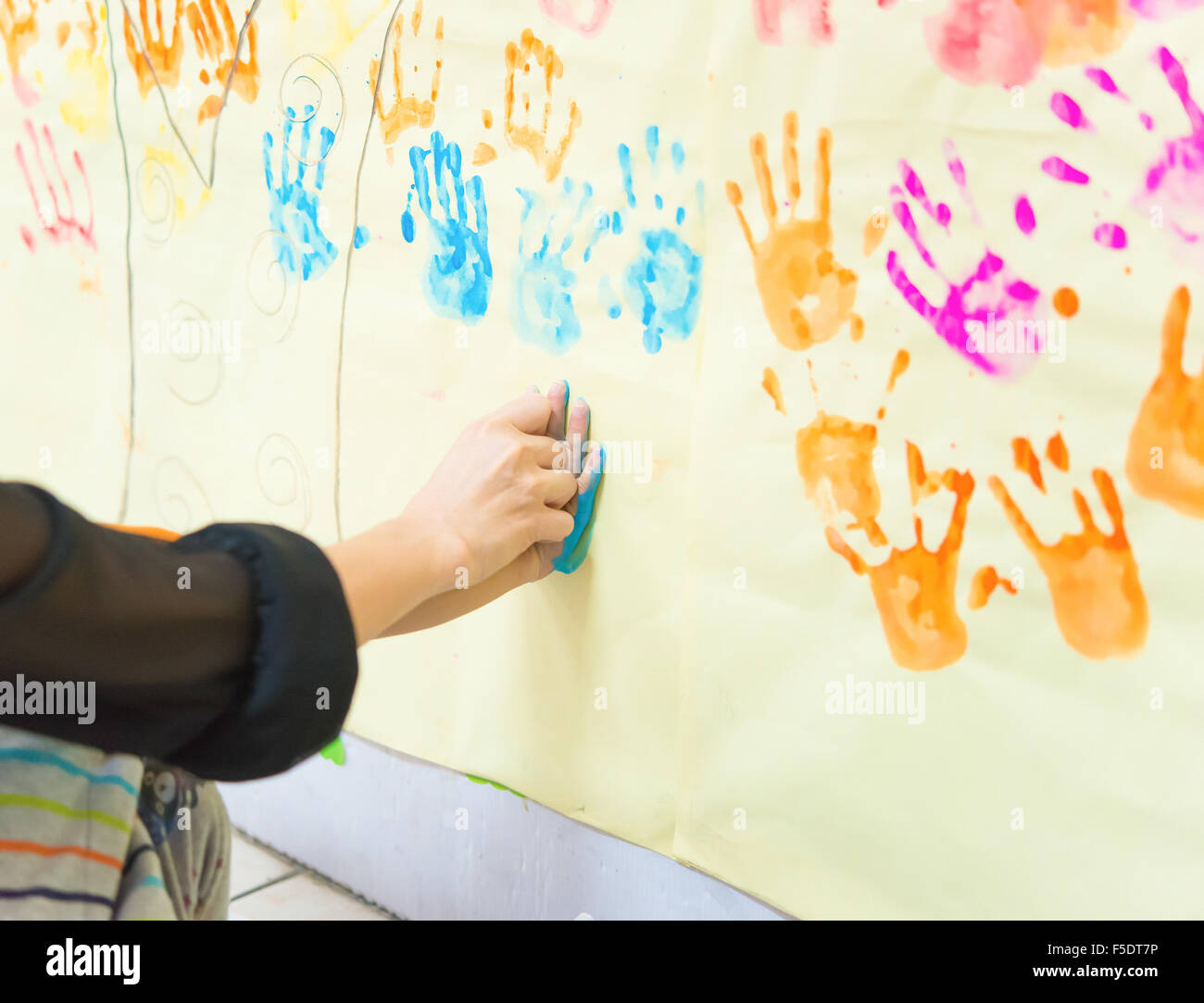 mother helps her young kid to make a hand print Stock Photo